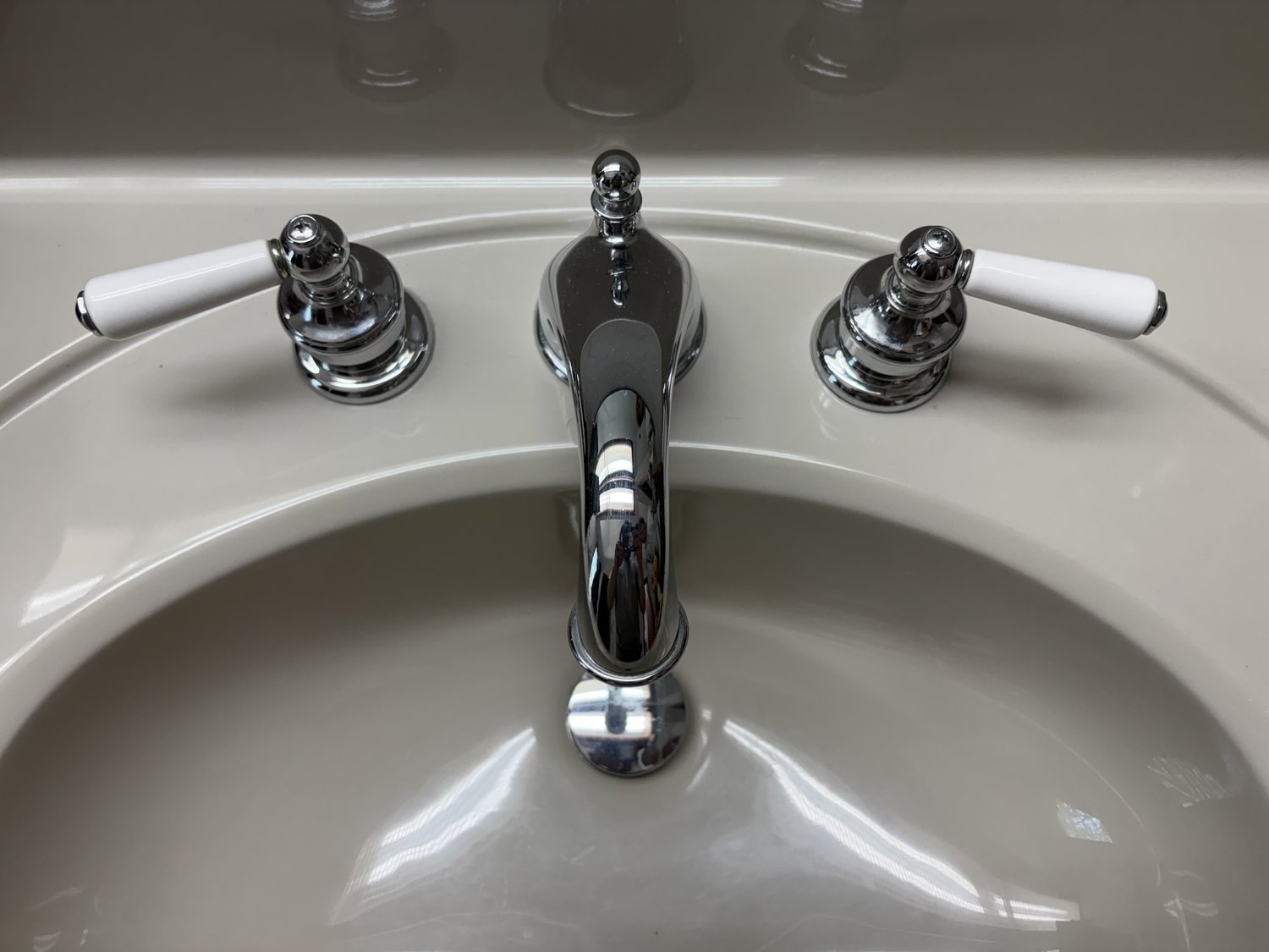Close-up of a chrome bathroom faucet with porcelain lever handles installed on a clean white sink