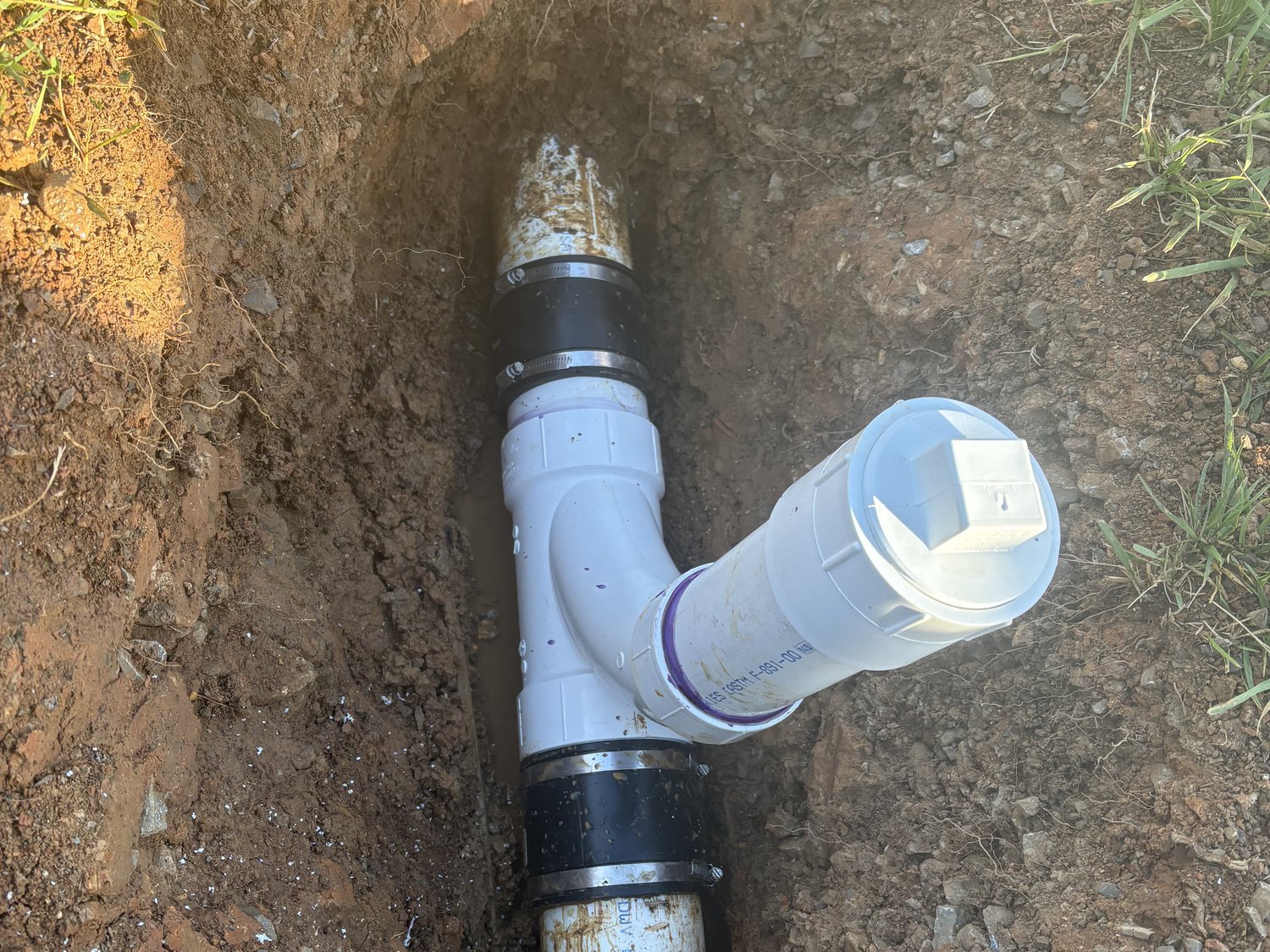 Replaced PVC sewer line with rubber couplings in an open dirt trench